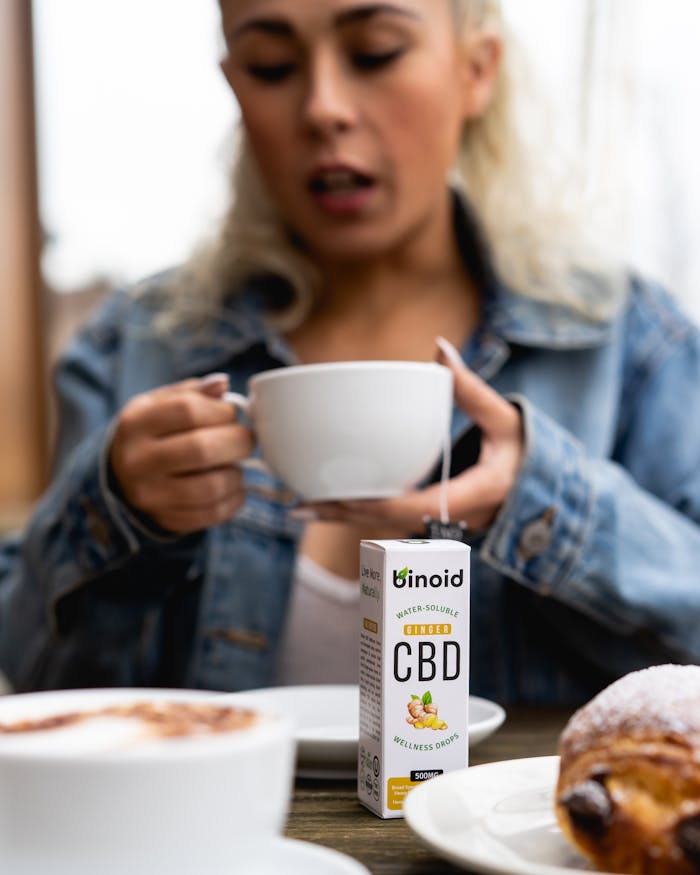 A woman savoring a CBD-infused coffee alongside a pastry, promoting wellness lifestyle.